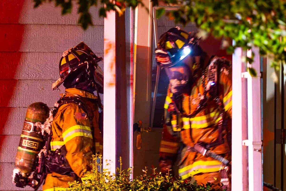 Firefighters work near the front entrance of a home following an early morning residential fire in the 5200 block of Jacksnipe Court on Sunday in West Richland. The fire spread from the attached garage into the home and attic