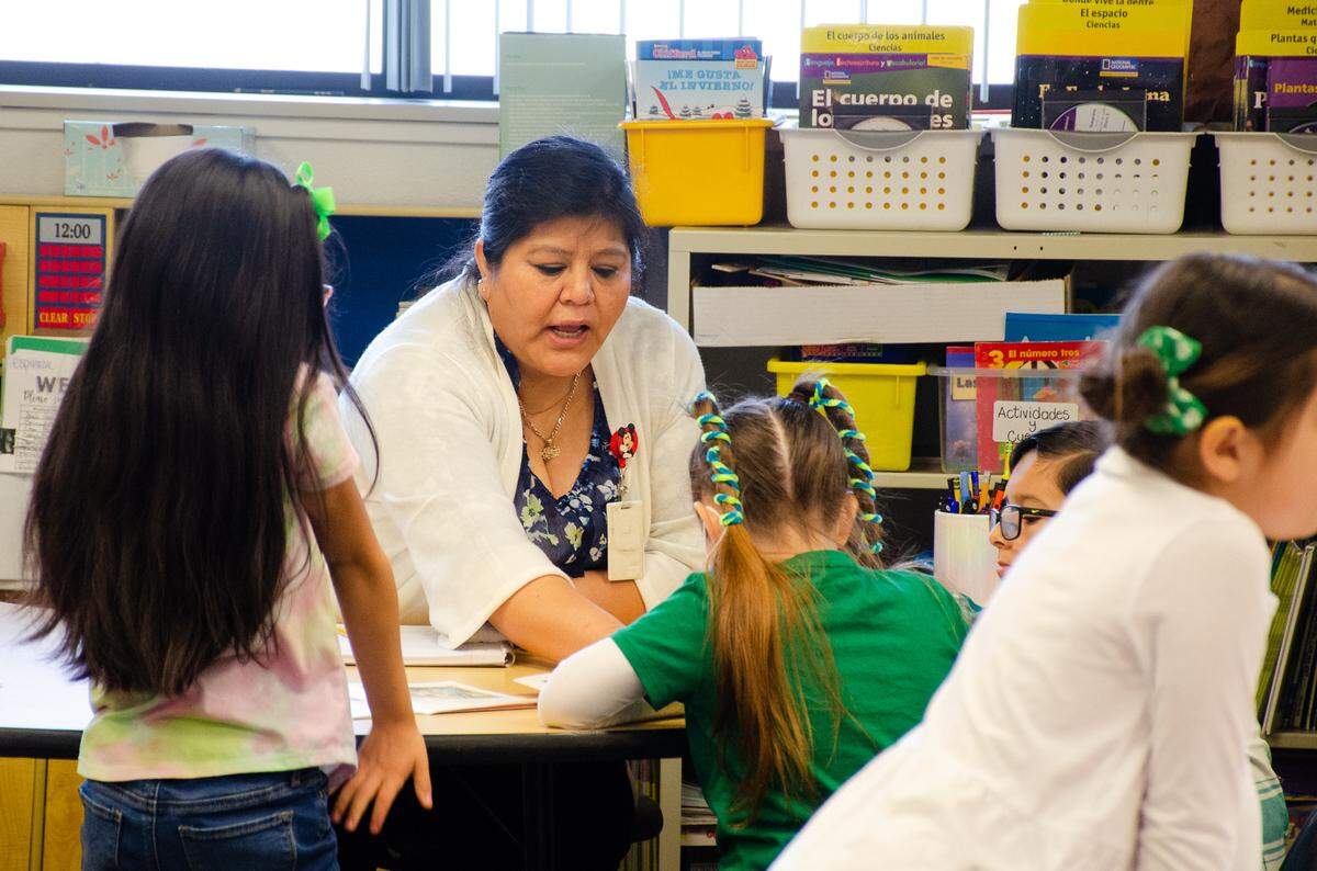 Pasco school officials are looking for $5.4 million in savings to balance the 2024-25 budget. Kindergarten dual language teacher Minerva Espinoza talks with students at Mark Twain Elementary School. in 2022.