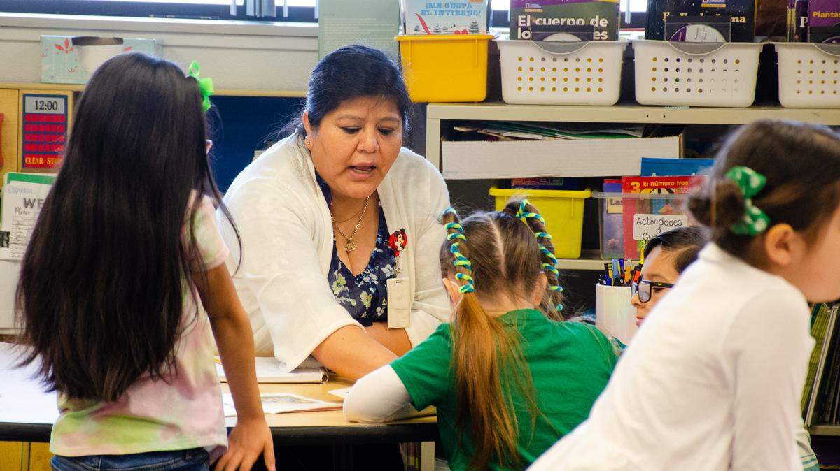 Pasco school officials are looking for $5.4 million in savings to balance the 2024-25 budget. Kindergarten dual language teacher Minerva Espinoza talks with students at Mark Twain Elementary School. in 2022.