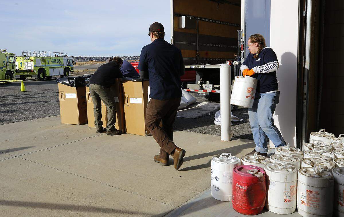 Workers from Clean Harbors Enviromental Services prepare to package and haul away aqueous film-forming foam from the Pasco Fire Department Fire Station at the Tri-Cities Airport.