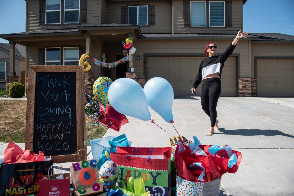 Rachel Russell waves to friends as they drive by her house to celebrate her son, Rocco’s sixth birthday. She organized the drive-by parade when social distancing to help deter the spread of COVID-19 prevented a traditional party.