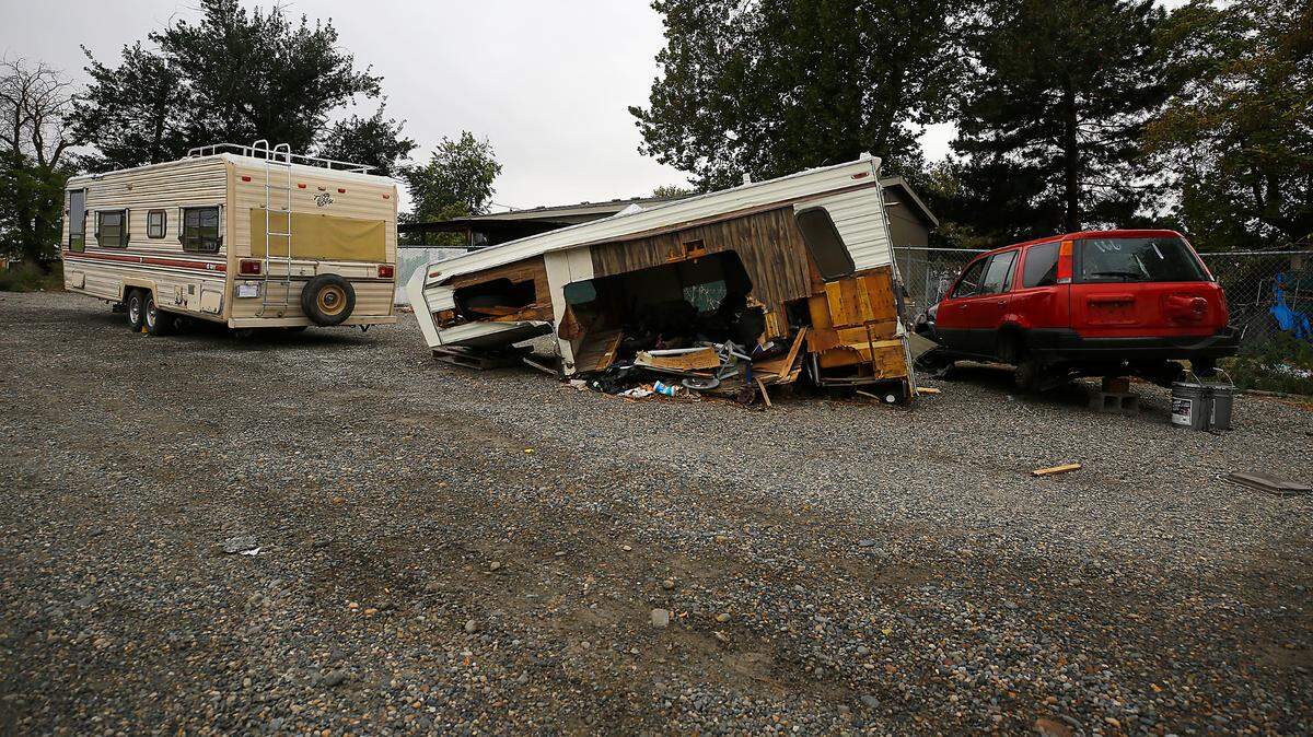 A derelict camper, trailer and vehicle sit in a vacant gravel lot on West 7th Avenue at Highway 395 in Kennewick.