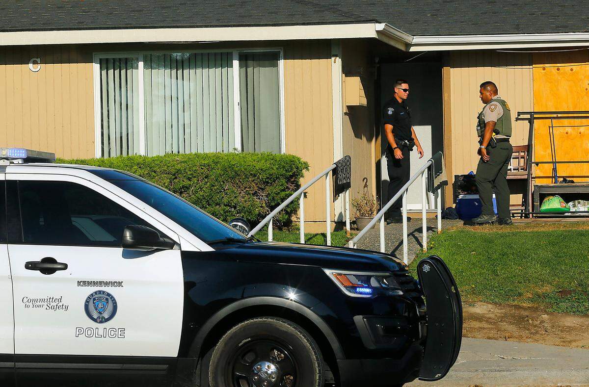 A Kennewick police officer and a Benton County Sheriff deputy stand outside a unit at the Spring Meadow Apartments in Kennewick following an overnight standoff at the site. The Tri-City Regional SWAT team responded earlier in the day to the Fifth Avenue apartment complex after a group reportedly held a woman at knifepoint.