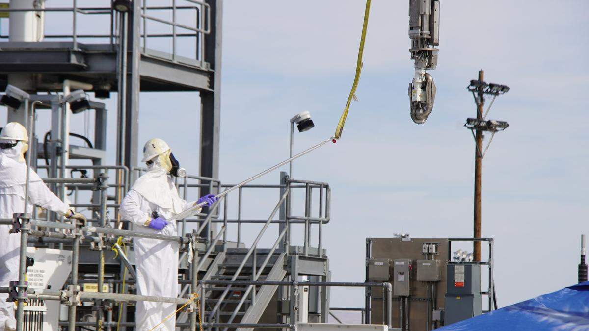 H2C workers install a high-pressure nozzle inside an underground tank storing radioactive waste to help mix and move the sludge to prepare to transfer it for treatment at the vitrification plant.