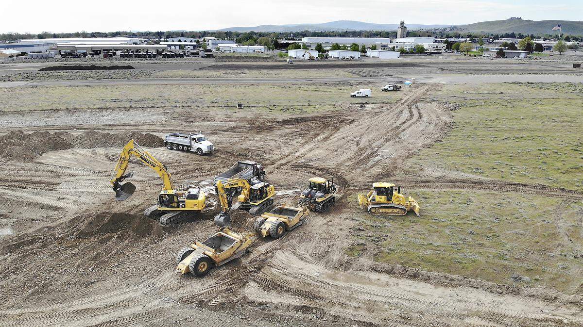 Heavy equipment excavates Friday at the former Vista Field Airport in Kennewick for the first phase of what will eventually be a walkable neighborhood with homes, offices, stores, restaurants, parks and a canal-like water feature. The Port of Kennewick awarded a $4.9 million contract to Total Site Services of Richland to build the roads and other infrastructure.