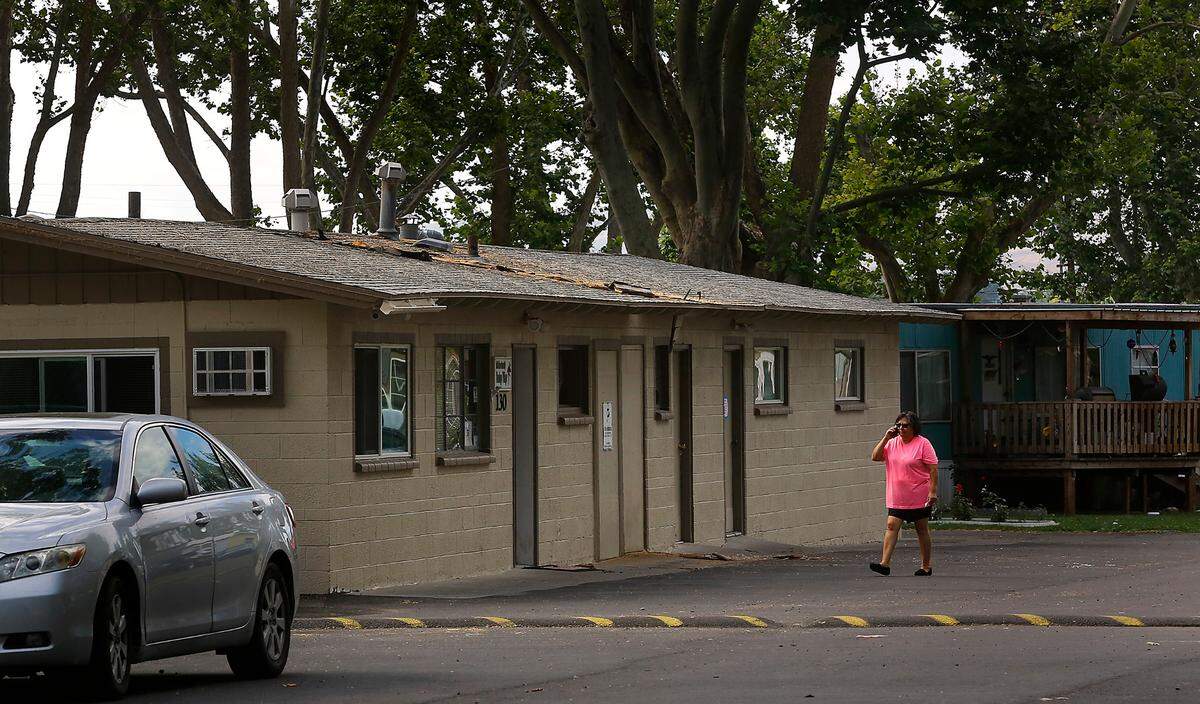 A woman uses a cellphone while approaching the fire damaged office building Tuesday morning at the Flamingo Village Mobile Home Community in Pasco. Fire officials have not yet determined the cause of the Fourth of July fire but discovered the ground littered with fireworks remains when they arrived to extinguish the Monday night blaze.
