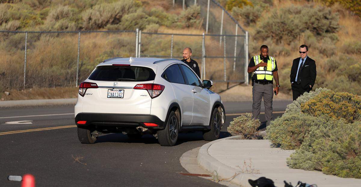 Andrew Clark, right, Benton County Chief Deputy Prosecuting Attorney, stands with Richland police officers investigating the early morning fatal collision involving a bicyclist and vehicle on Duportail Street at City View Drive.
