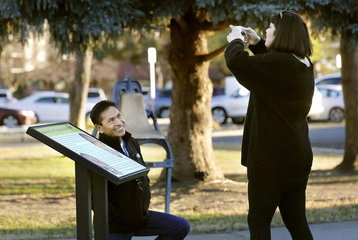 Javier Sanchez kneels near an informational sign about Kennewick Man displayed outside the East Benton County Historical Museum in downtown Kennewick. Watch a video at: tricityherald.com/video