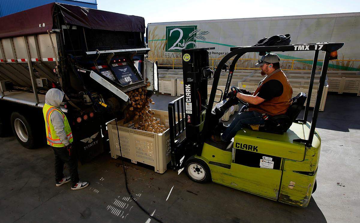 Truck driver Alejandro Diaz, left, controls the conveyor belt speed as 2nd Harvest employee Justun Anderson operates a forklift during the unloading of 73,000 pounds of donated potatoes at the Pasco warehouse for 2nd Harvest.