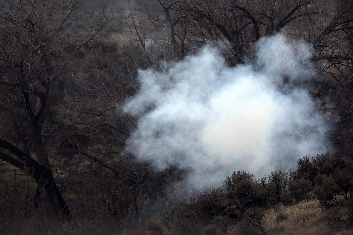 A cloud of white smoke from a diversionary device commonly known as a flash bang hangs in the air in the ravine just south of Kennewick where detectives encountered a Kennewick murder suspect.