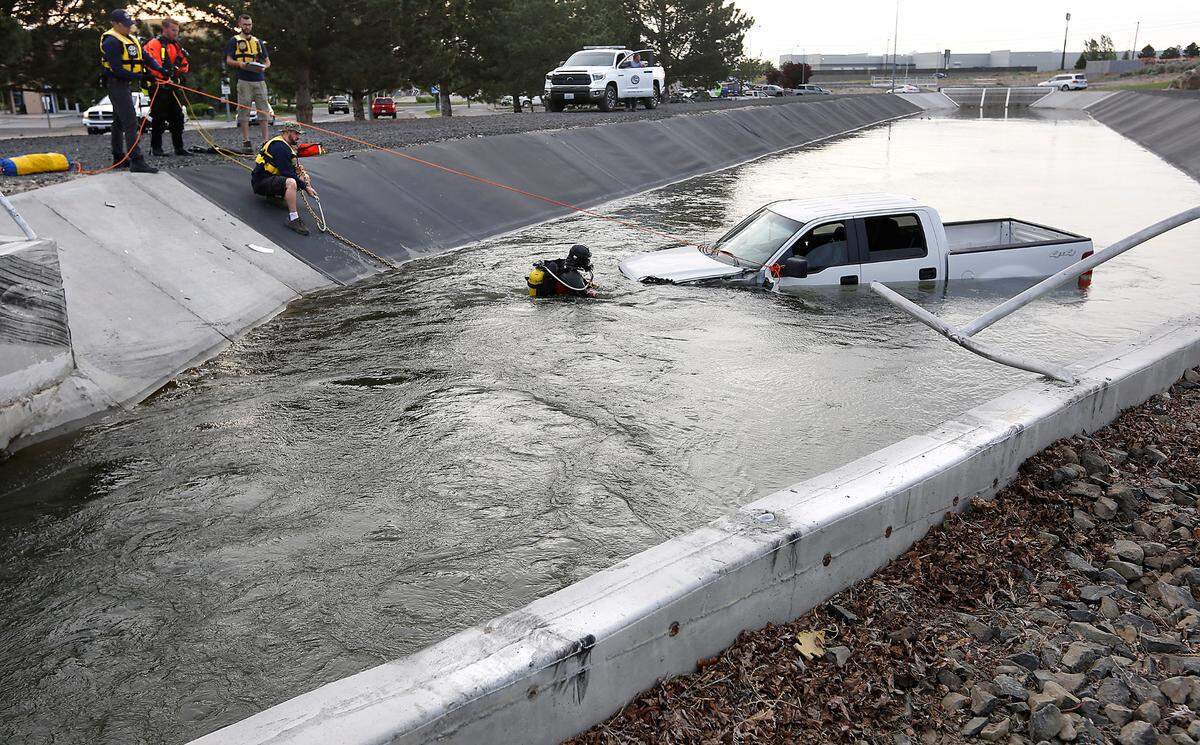 Members of Columbia Basin Dive Rescue help connect tow truck chains to a submerged pickup early Tuesday morning after Kennewick firefighters used an extension ladder to lead pickup driver Robin Berry,to safety after she vaulted her late-model Ford into the irrigation canal at West 27th Avenue and Creekstone Drive in Kennewick.