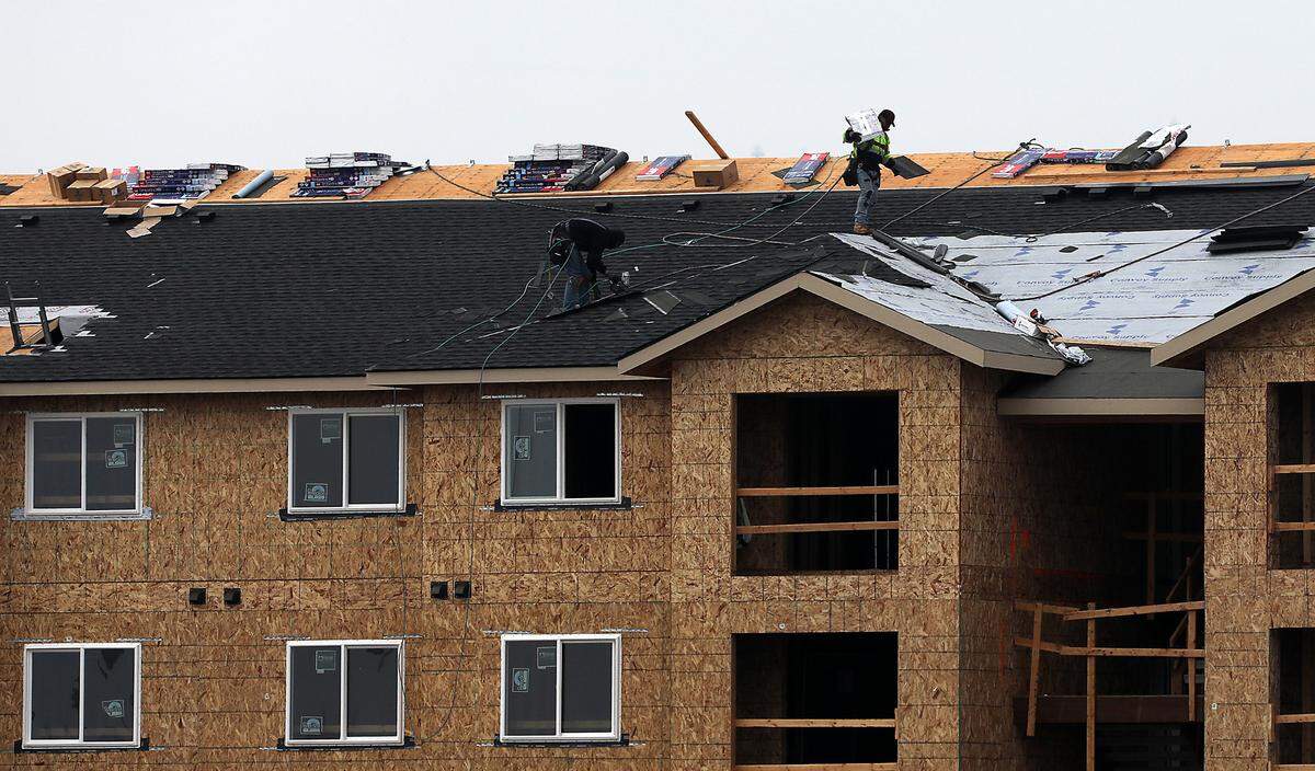 A pair of roofers work on top of one of the new buildings on the 5-acre site for the Bradley Boulevard Apartments complex.