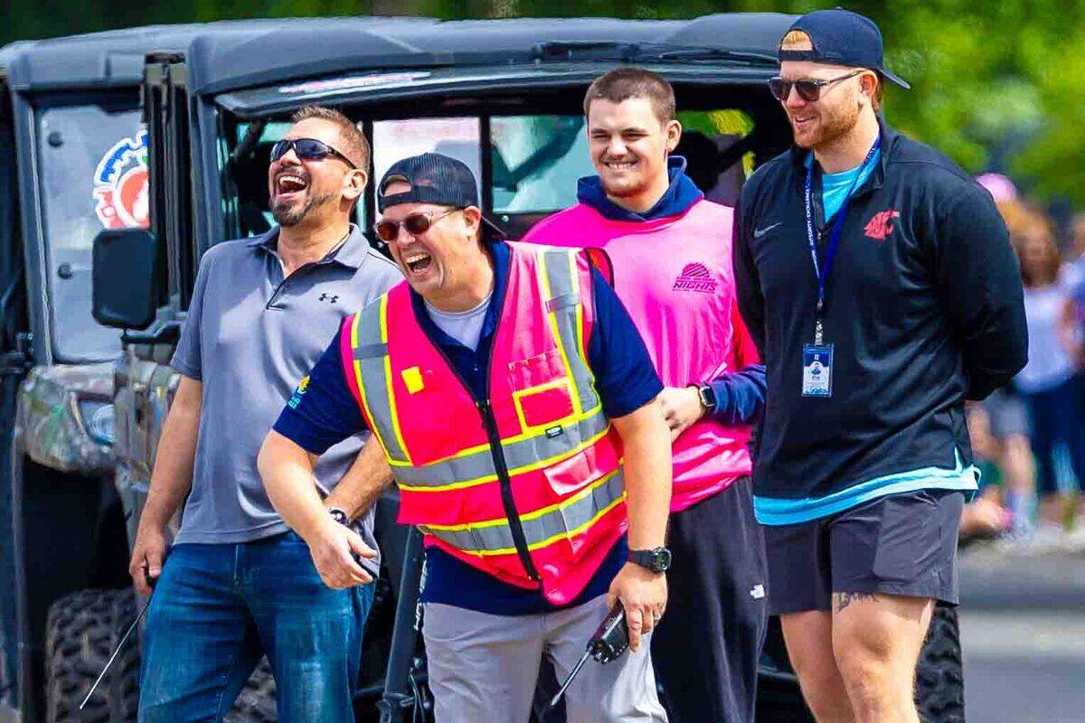Volunteers share a laugh while helping direct the Slow Drags on Saturday during Cool Desert Nights along George Washington Way in Richland. The annual event drew large crowds to watch classic cars cruise through the city’s Uptown district.