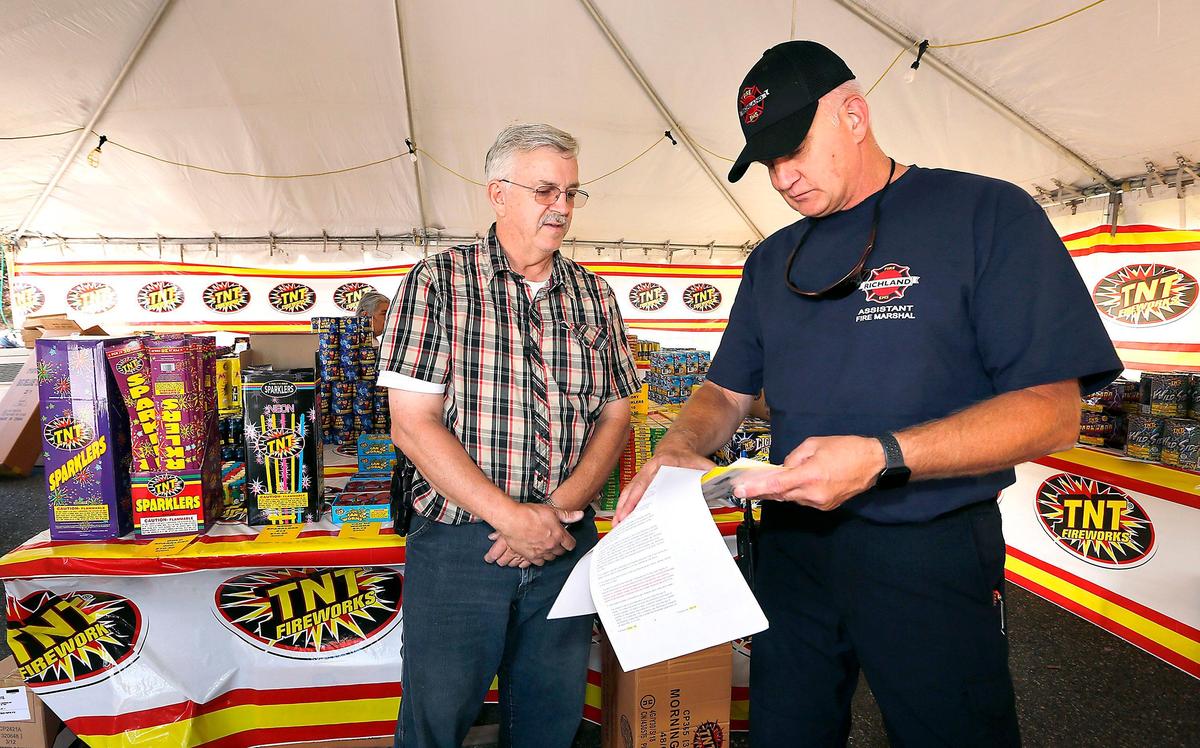 Troy Kenworthy, left, and Lt. Ken Buechler, Richland Fire Department assistant fire marshal, go over paperwork during Friday morning’s inspection of the firework stand in a grocery store parking lot on Gage Boulevard near Leslie Road in Richland. Buechler was assigned to check several stands in the south Richland area before the statewide sales of consumer fireworks commenced at noon. Kenworthy said the sales stand is operated as a fundraiser for the United Pentecostal Church Apostolic Temple in Kennewick. Watch a video at: tricityherald.com/video