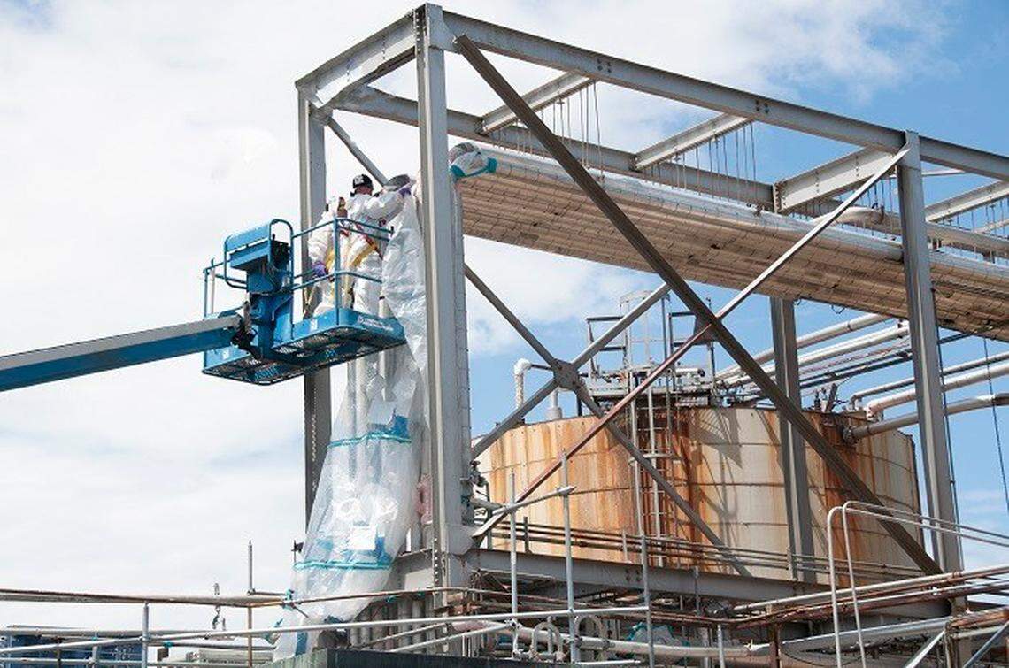 Crews at the Hanford site’s PUREX plant install bags on a piping system before removing material containing asbestos as part of environmental cleanup of the nuclear reservation.