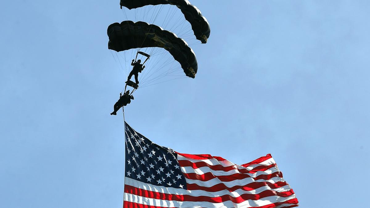 Members of the military’s SOCOM Para-Commandos Sky Diving Team deliver a huge U.S. flag during Saturday’s Tri-City Water Follies boat races and air show event in Kennewick’s Columbia Park.