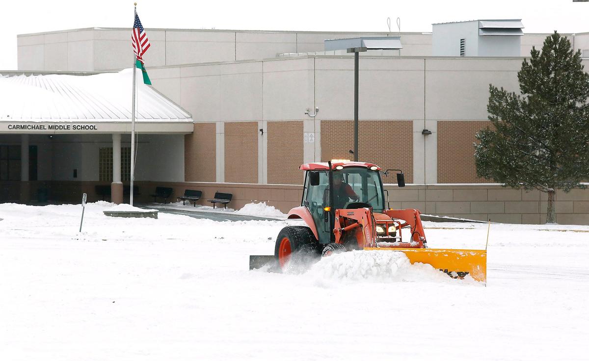 A tractor outfitted with a snow plow blade clears the parking lot of Carmichael Middle School early in Richland.