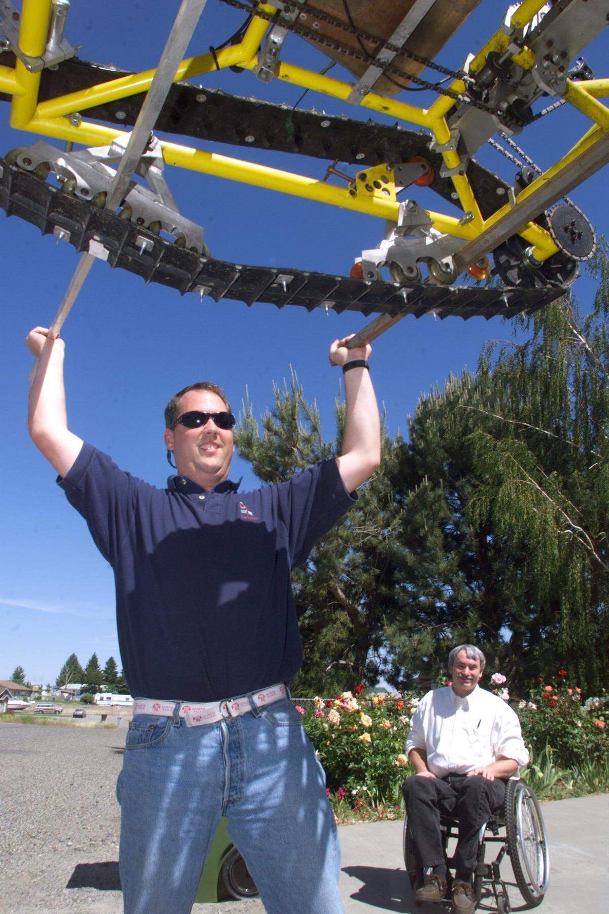 Pete Rieke watches from his wheelchair as climber Phil Ohl helps lift Rieke's snowpod onto the top of Ohl's truck in 1999 before their Mt. Rainier climb.
