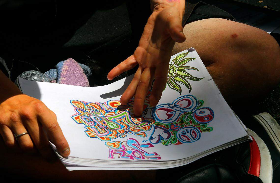 Stevo Wold gestures at one of his drawings while explaining the meaning of the colors, symbols and lettering he’s incorporated into the artwork. Wold, 29, says he’s been living on the streets since he was 16 years-old.