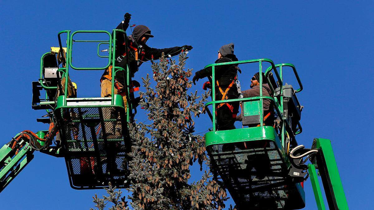 Richland city workers use a pair of boom lifts to place Christmas lights on the nearly 50-foot evergreen at John Dam Plaza along George Washington Way.