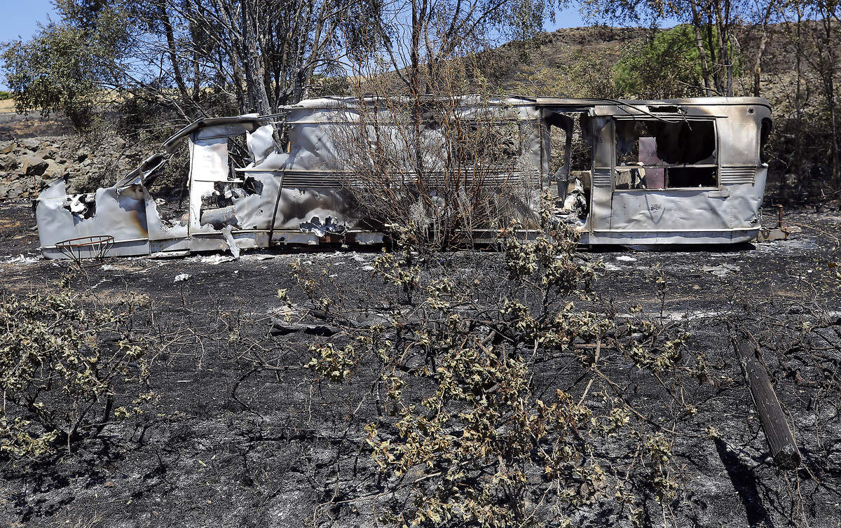A fire damaged trailer sits in the charred landscape on Chaffee Road near North District Line Road following the weekend’s wildfire between Benton City and Prosser.