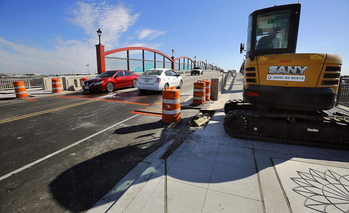 A down-sized excavator sits on the sidewalk near steel plates covering the work at the transistion from pavement to concrete bridge decking on the Lewis Street Overpass in Pasco. 