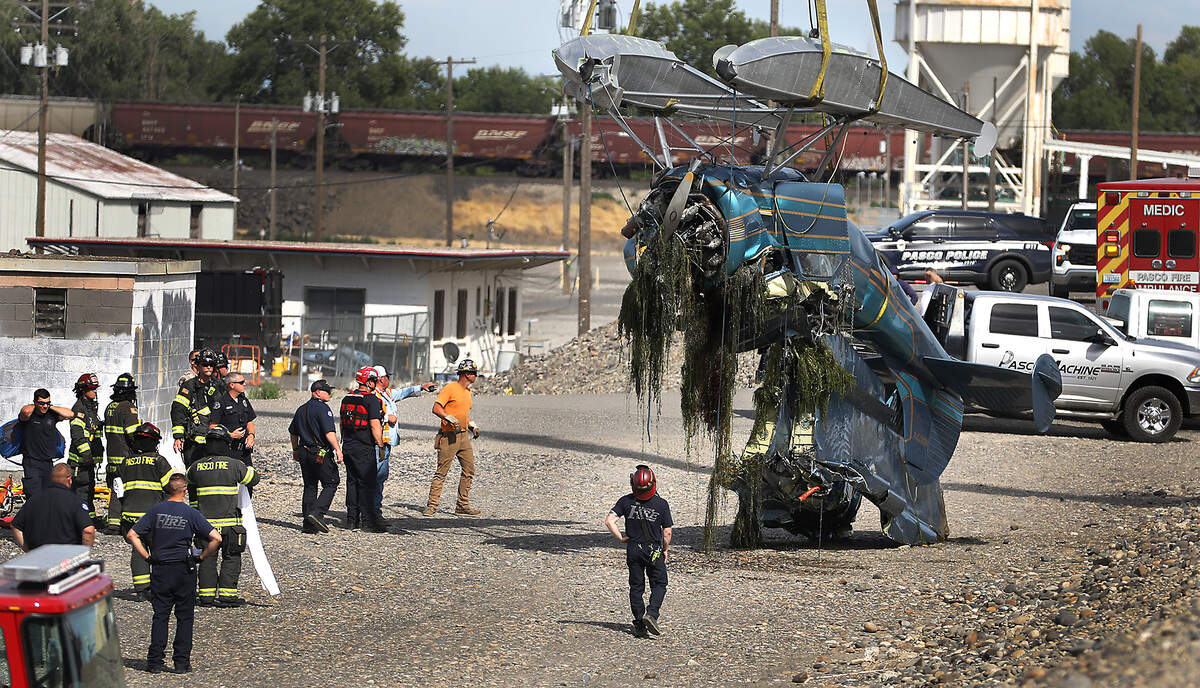 A crane on the Pasco shoreline sets down the crumpled floatplane that hit a power line over the Columbia River on Wednesday. Two men onboard were killed. Editor’s note: This image has been digitally altered to obscure graphic details.