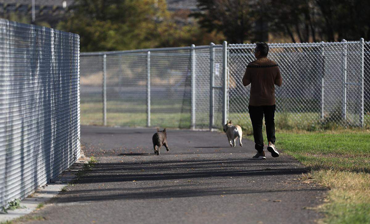 A pet owner and his two dogs pass the fenced section of the new dog park in the east end of Columbia Park. 