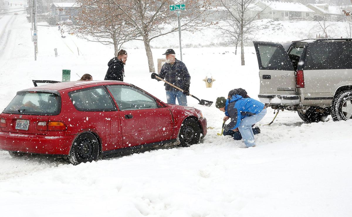 A group of Good Samaritans help free a motorist in a low-slung Honda sedan that became high-centered on deep ruts of snow Monday on West Seventh Avenue in Kennewick. After a clearing away some snow they were able to attach a tow strap and free the car from the intersection.