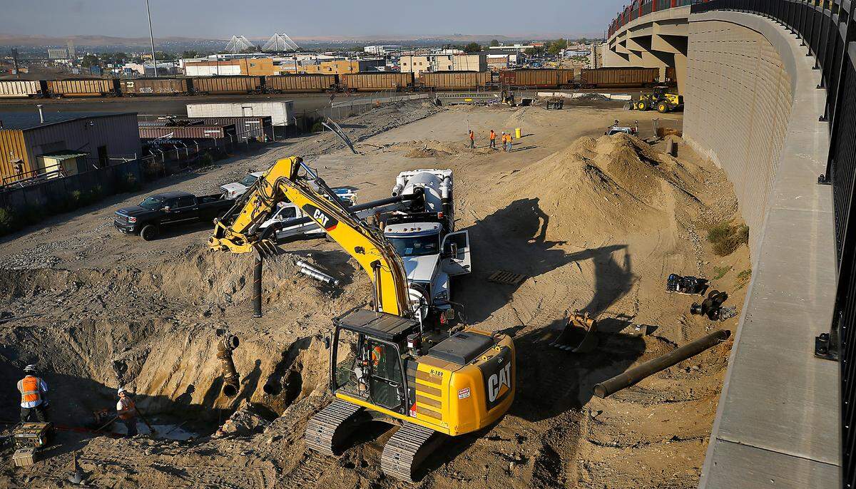 An excavator lifts out a section of old water main pipe early Thursday as part of the ongoing Lewis Street Overpass Project in Pasco. Crews were connecting a new water main under the railroad tracks.