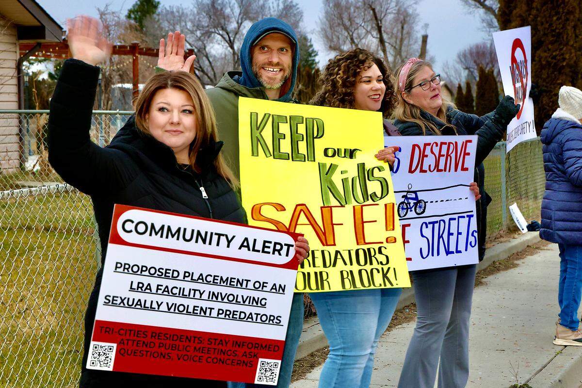 Kira Sutherland, left, Daniel Bauer and wife, Riana Bauer, residents of West 8th Avenue, protest Monday evening at Edison Street and West 8th Avenue in Kennewick. The group is opposed to a decision to allow a home for Level-3 sex offenders on West 8th Avenue.
