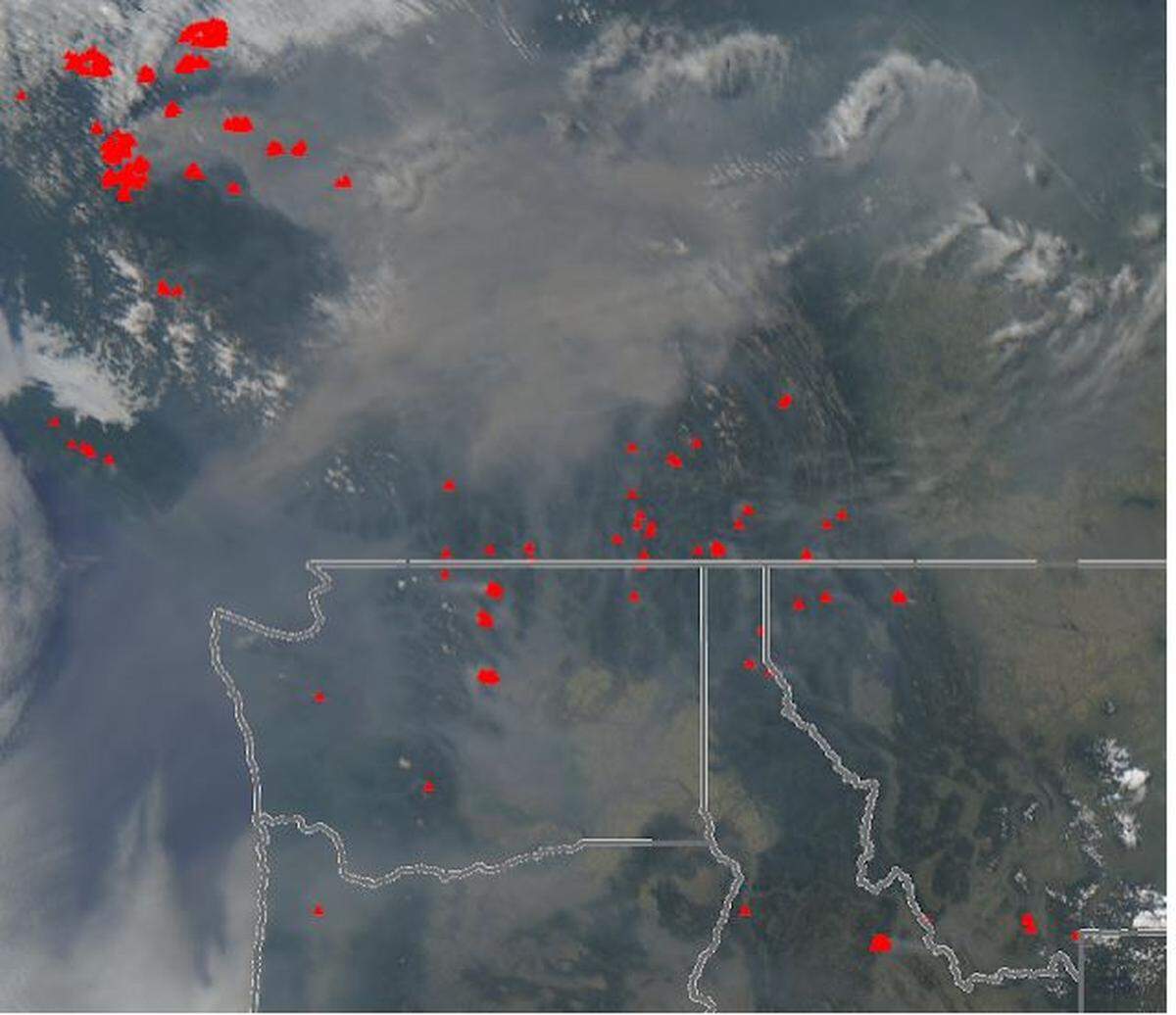 Red marks on a satellite image show where fires are burning in Canada and the Pacific Northwest.