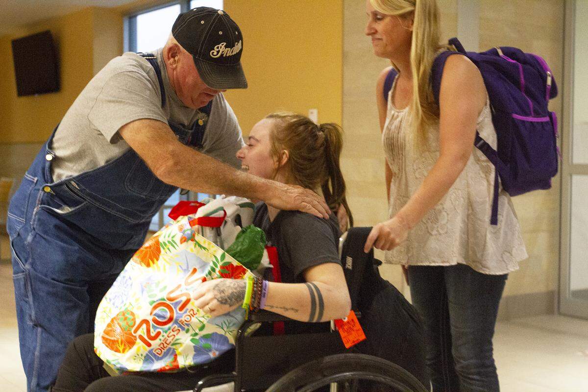 Dave Whitsett, left, reaches down to hug his granddaughter Danika Whitsett when she arrived Wednesday night at The Tri-Cities Airport in Pasco. Family friend Treana Meginnis, right, accompanied Danika home from Arizona.