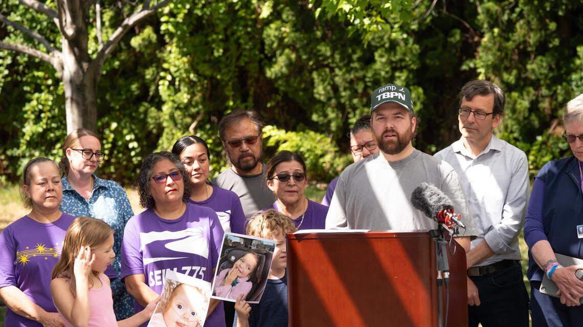 Britton Winterrose is a director for Microsoft with the deluxe healthcare that job provides, but he still relies on Medicaid to help care for his 5-year-old daughter Leda. Two of his other children hold pictures of her at a Thursday press conference with Gov. Bob Ferguson in Kennewick.