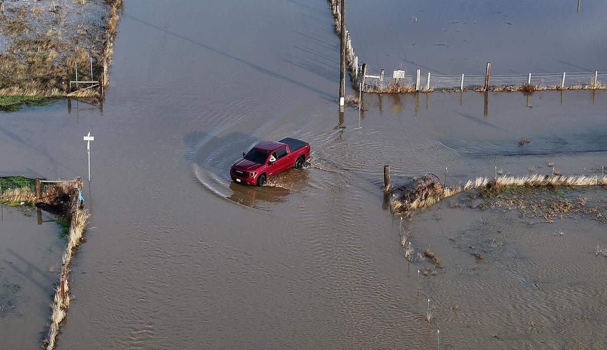 A  pickup creates a wake Friday morning in the Yakima River floodwater covering the intersection Gomer and Jones Roads near Van Giesen Street in Richland.
