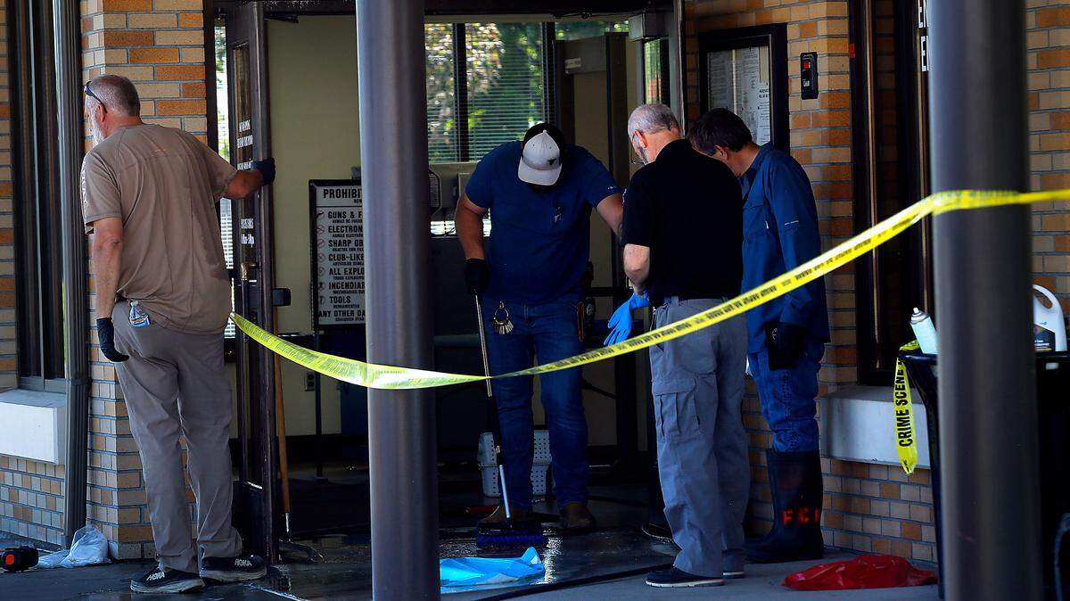 Workers carefully scrub and clean away blood discovered on the sidewalk and the entryway to the security building at the Franklin County Courthouse early Monday morning in Pasco.