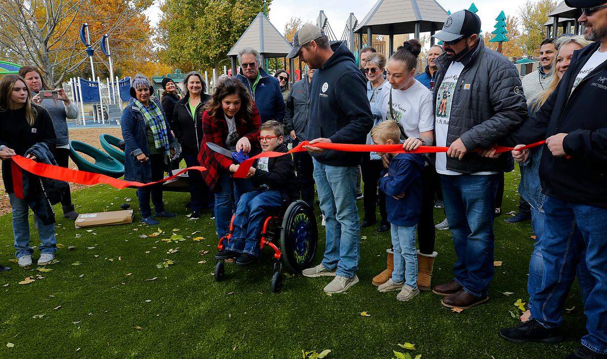 Kason Creed is surrounded by about 50 friends, family members and well-wishers as he cuts the ribbon to dedicate a new inclusive playground in Columbia Park.