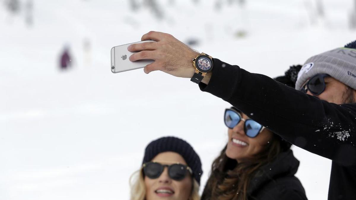 In this photo taken Dec. 16, a group huddles together to take a selfie photo on a cell phone at the Paradise area at Mount Rainier National Park. Spotty or no cellular service has been the norm at the nation's fifth oldest park south of Seattle, but that could change soon. Mount Rainier National Park is considering proposals to provide cellular service in the park, setting off debates about whether people enjoying the park and surrounding wilderness areas should have access to calls and social media while in nature.