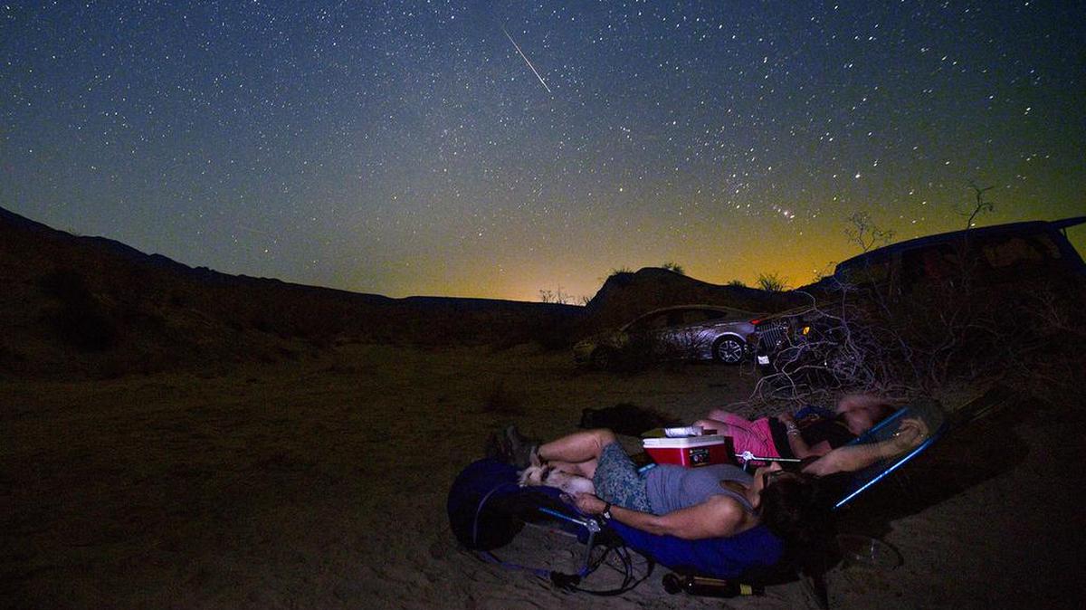 College photography professors Donna Cosentino and Judith Preston watch a Perseid meteor streak through the sky above California’s Anza Borrego Desert State Park in 2015. The orange glow is from the lights of Salton City, about 10 miles away.