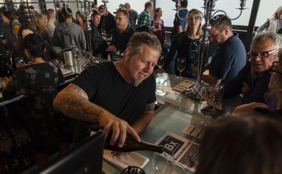 Brennon Leighton, who trained at Ste. Michelle Wine Estates, pours wine for guests at the Jet City tasting room near Boeing Field in Seattle.