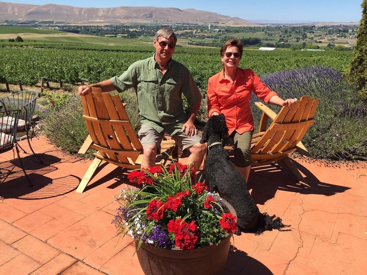 Larry Pearson and his wife, Jane, entertain Hugo, the youngest of their two standard poodles, on their Red Mountain patio at Tapteil Vineyard Winery in Benton City, Wash.