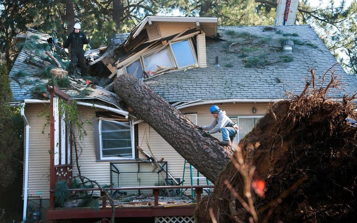 Jake Hines, left, and Ross Rukke, of Capstone Construction, work to remove a fallen tree in Spokane after deadly storms swept through the state leaving many without power.