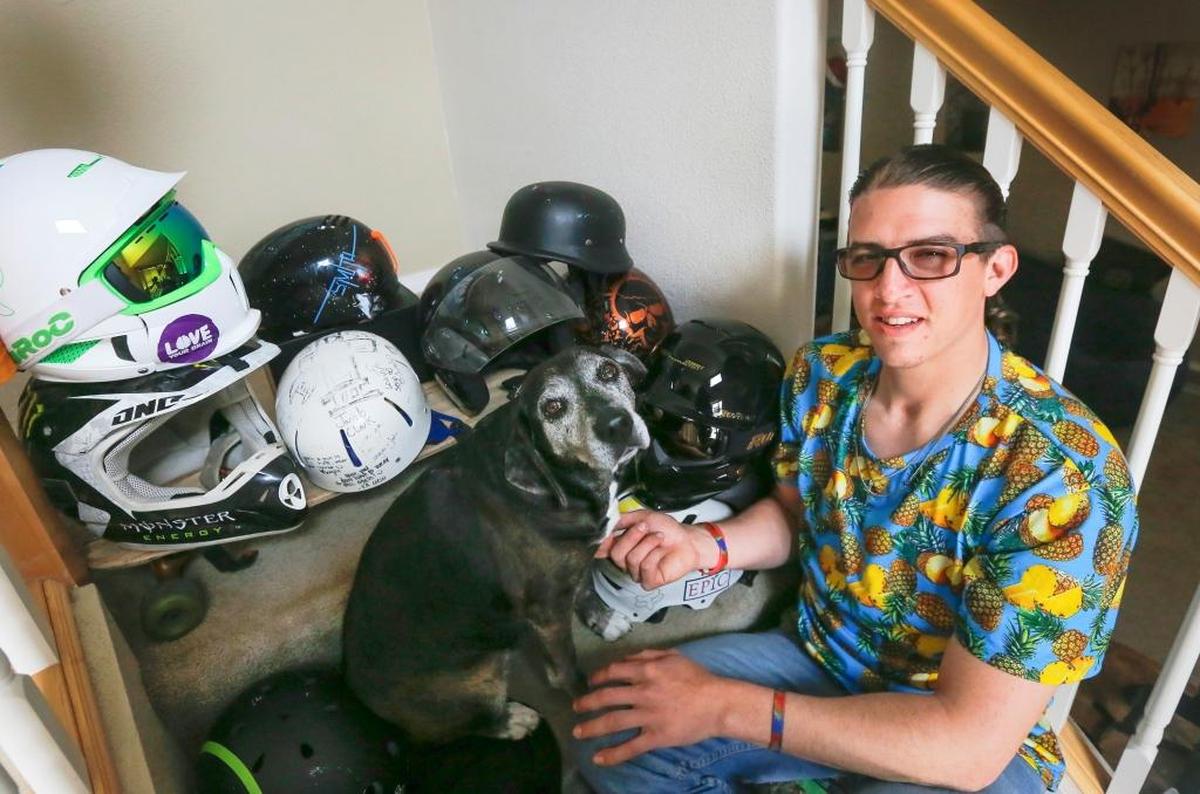 Sean McClintock sits on his stairs with Nemo his dog and all his helmets inside of his home in Pasco on Thursday. McClintock feels like his purpose is to remind other to be safe, to wear a helmet and protect your brain. When he sees someone without a helmet, he will give them one or give them money to buy one.