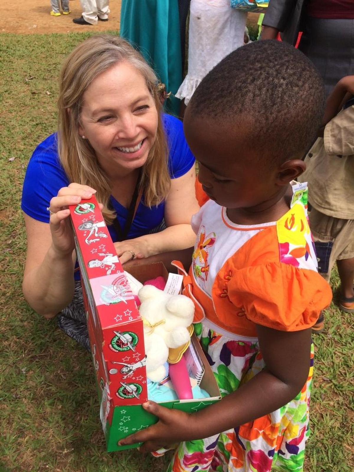 A Rwandan little girl gets her first glimpse of the gift-filled shoebox with the help of Tricia MacFarlan. The Tri-Cities Area Coordinator in Benton County was hand-delivering the Operation Christmas Child boxes this summer.