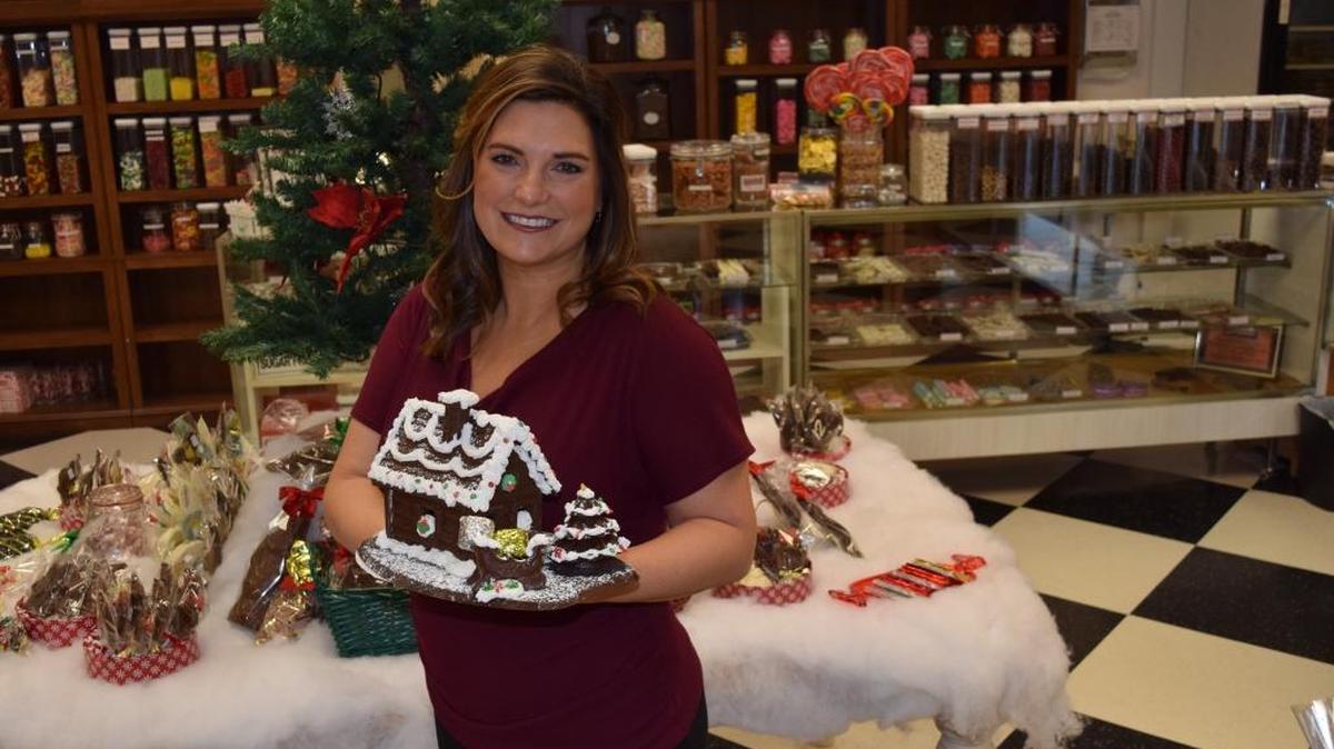 Baum’s House of Chocolate & Gourmet Popcorn co-owner Mindy Sandlin adds a handmade chocolate house to the variety of Christmas candies on display. “In every fiber of this business, God is here,” Mindy said. “I couldn’t do it without him.”