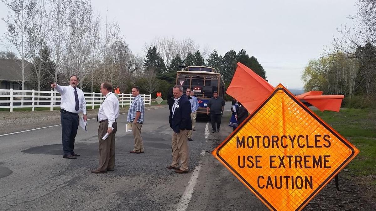 Cary Roe, Kennewick’s public works director, left, discusses a failed section of West 33rd Avenue with City Councilman Don Britain during a trolley tour of the city’s worst potholes Tuesday. Councilman Matt Boehnke is in the background, along with Josh Soggle, the city’s streets crew leader.