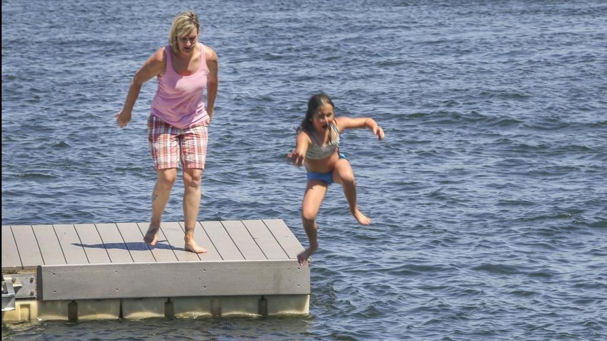 Michelle Fricke and her daughter, Paisley Fricke, 8, jump off a dock to cool down in 105-degree weather Friday afternoon at Howard Amon Park in Richland. The high Saturday is expected to be 100 degrees, according to the National Weather Service.