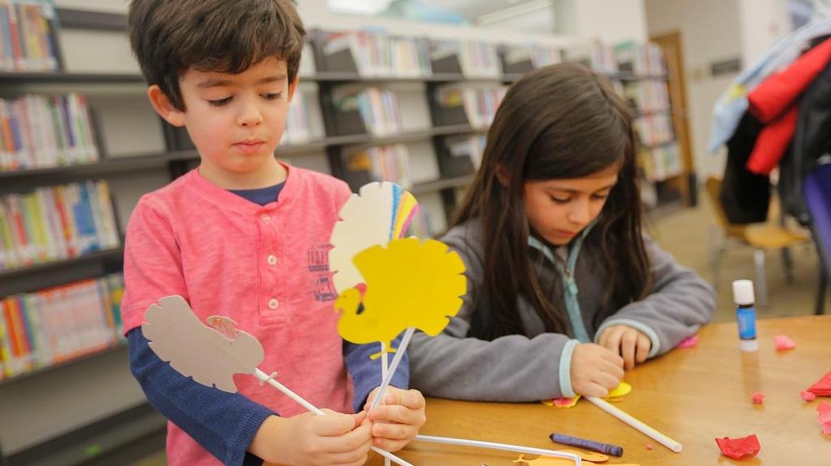 Thomas Larimer, 5, looks at his paper turkeys that he decorated Tuesday as his friend Alice Beirao, 5, continues to decorate her turkey during the Thanksgiving & Autumn crafts event at the Richland Library.