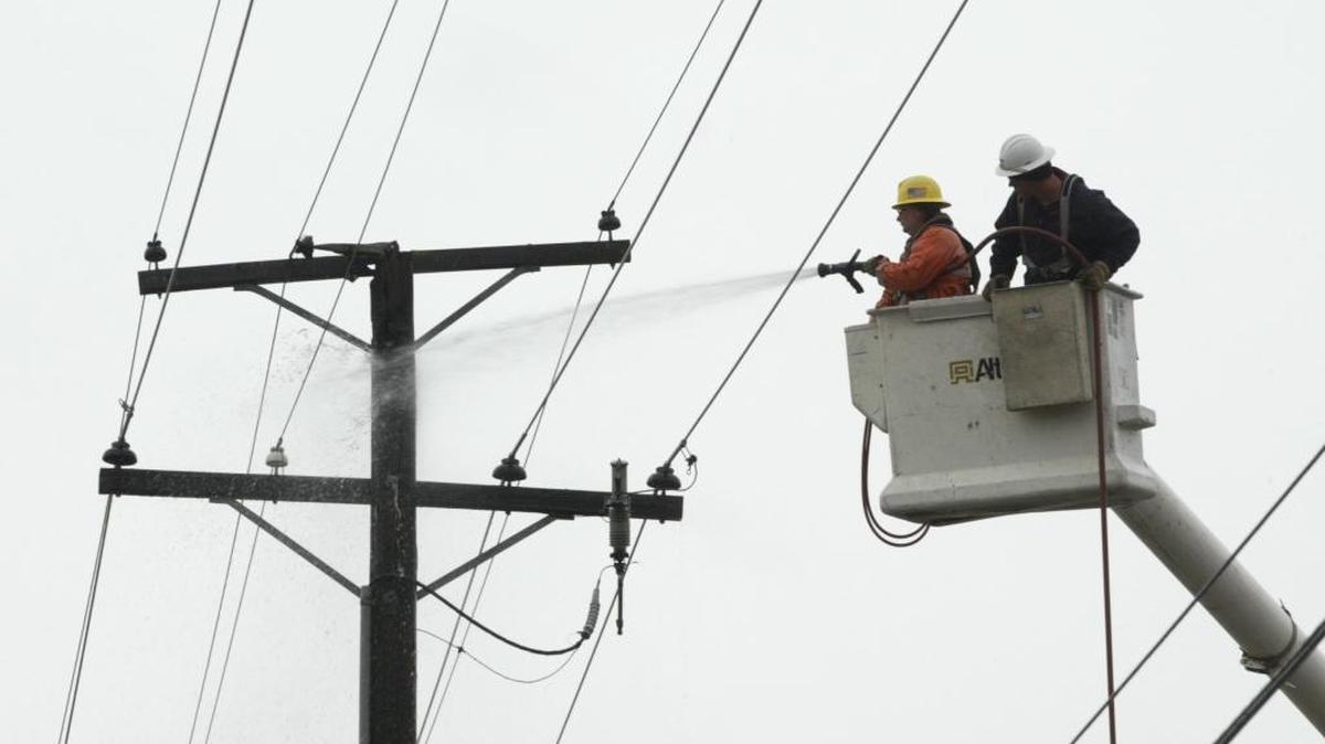 Using a fire hose borrowed from a Pasco fire truck, Franklin PUD workers Jim Zacha, left, and Darren Idler extinguish a smoldering utility pole on March 26, 2005, in front of 2120 W. Pearl St. A glass insulator on the double circuit pole broke down and caught fire and caused a power outage.