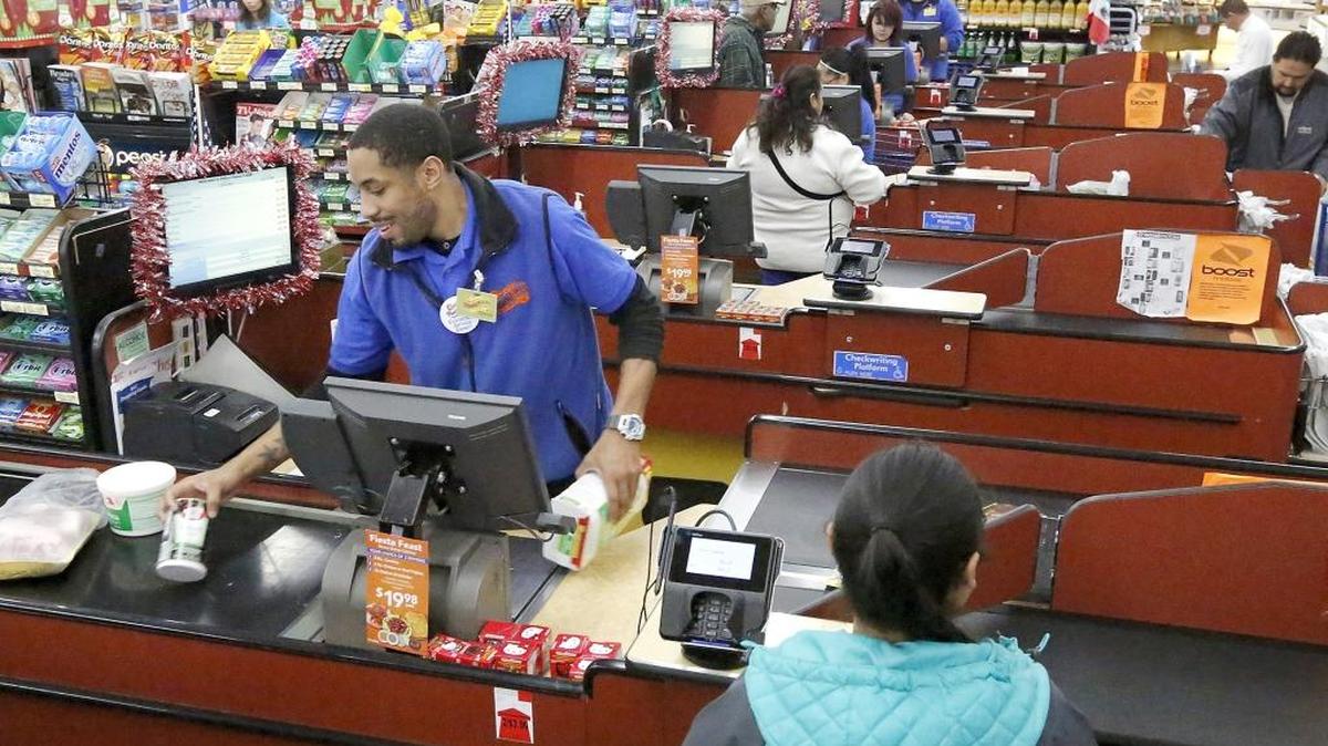 Terran Richardson, an employee at Fiesta Foods, joins a group of cashiers Tuesday checking out customers at the busy Pasco grocery store.
